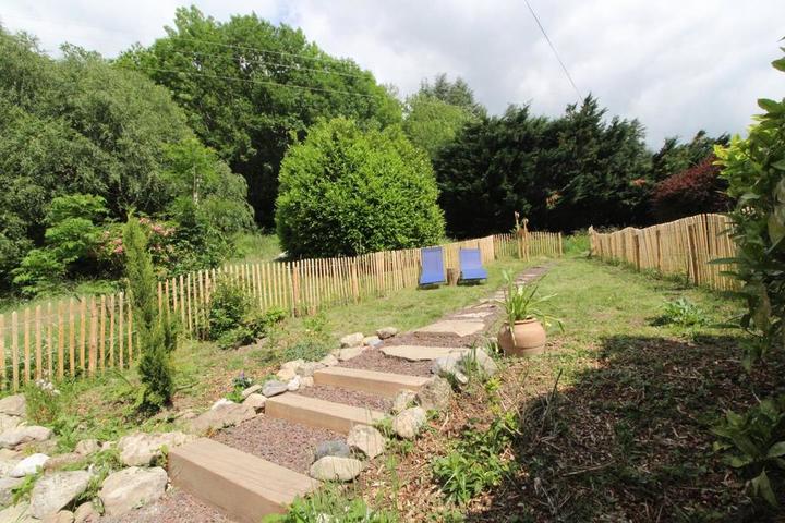 Jardin clôturé avec chaises longues pour détente